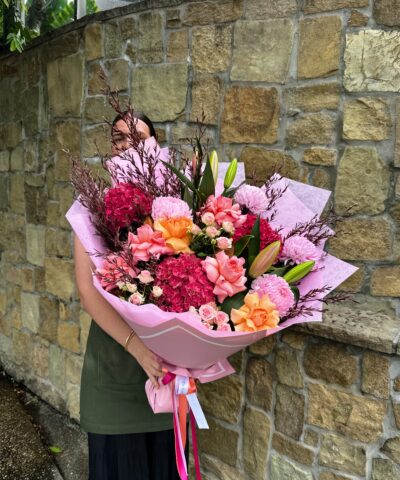 Large pink and peach floral bouquet featuring hydrangea, roses and chrysanthemums wrapped in pink paper