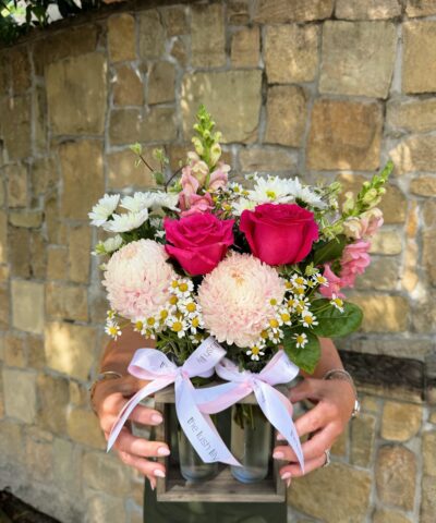 Meet our Blush Garden Duo — a sweet and stylish floral arrangement designed to capture the beauty of a soft, romantic garden in full bloom. Thoughtfully arranged in two elegant glass vases, this charming duo is presented in a rustic wooden holder and finished with The Lush Lily’s signature satin ribbon for that extra luxe touch. Featuring a delicate mix of blush chrysanthemums, premium pink roses, dainty chamomile-style daisies, and seasonal filler flowers, the Blush Garden Duo is all about soft textures, feminine tones, and effortless beauty. Each bloom is carefully selected fresh from market to ensure a high-quality, long-lasting arrangement that feels both whimsical and refined. This unique double-vase design makes it incredibly versatile — perfect as a centrepiece, bedside styling, or a thoughtful gift that feels a little different from your traditional bouquet. The two vases can be styled together for a fuller look or separated to spread the love across multiple spaces. Whether you’re celebrating a special moment or simply sending a little love, this arrangement is designed to suit a wide range of occasions: 💗 Perfect for: * Mother’s Day * Birthdays * Get Well Soon gestures * Thank You gifts * New baby celebrations * Thinking of You moments * Just because At The Lush Lily, we pride ourselves on creating floral designs that feel as though they’ve been freshly picked from a garden. While we always aim to replicate the colours and style pictured, flowers may vary slightly due to seasonal availability and market freshness. Rest assured, any substitutions will always be made with blooms of equal or greater value, maintaining the overall look, feel, and colour palette of this design. Each Blush Garden Duo is handcrafted with care by our talented florists and beautifully wrapped, making it ready to gift and guaranteed to impress. Enjoy same-day flower delivery across Brisbane when you order before our cut-off time — because beautiful flowers should never have to wait.