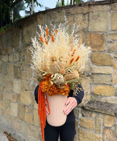 Amber Harvest dried and preserved flower arrangement with orange hydrangea, cream foliage, banksia and cascading orange amaranthus in a ribbed neutral vase.